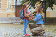 © Dragana Gordic - Parent and pupil of primary school go hand in hand. Woman and girl with backpack behind the back. Beginning of lessons. First day of fall.
