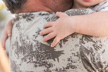 Child's Hand Embracing Adult In Camouflaged Clothing