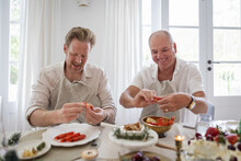 Two Men Deveining Prawns At Dinner Table