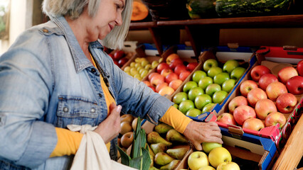 Latin senior woman shopping at farm market. Customer buying at grocery store. Small business concept