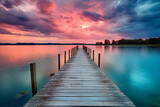 Fototapeta  - A wooden pier stretching into a large, dark lake at sunset. This evocative image captures the tranquil beauty of nature at dusk, inviting viewers to contemplate the serenity of the moment