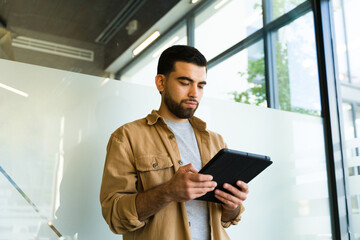 Wall Mural - Young businessman in casual clothing using a tablet computer for work