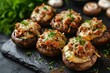Meat and cheese stuffed mushrooms on a black board
