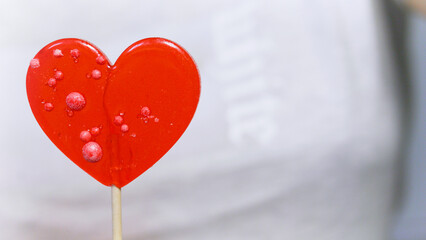 Valentine's Day concept. Heart-shaped lollipop on neutral neutral background.