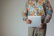 businessman in aloha shirt and trousers holding a laptop