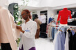 Clothing shopping mall department employee dressing mannequin in jacket and skirt formal wear. Fashion showroom african american assistant putting female outfit for office on model