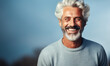 Joyful mature man with stylish white hair and beard, wearing a casual light sweater, radiating confidence and happiness on a light background