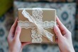hands holding a gift box with a magnified focus on the intricate lace ribbon