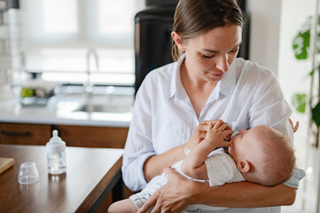 A young new mom bottle-feeding her newborn baby