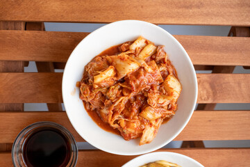 Noodles with mushrooms and vegetables and kimchi in white bowl close-up on gray background	