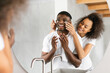 © Prostock-studio - Black young spouses sharing playful skincare routine at home bathroom