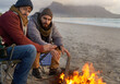 © AW/peopleimages.com - Campfire, friends and portrait with men by the beach at sunset with vacation and camping. Ocean, outdoor and together with travel and people in a trip and journey with fire and conversation by sea