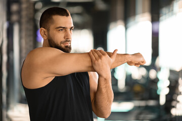 Canvas Print - Portrait Of Athletic Young Man Stretching Arm Muscles At Gym