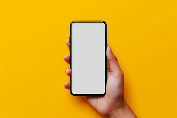 Hand holding the black smartphone with blank screen on yellow colour background.