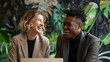© Patrick - Two smiling professional business people talking using laptop computer working in office. Happy colleagues or entrepreneurs team man and woman discussing corporate technology at workplace.