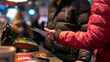 © sandsun - A person holding a smartphone with NFC technology uses it to make a payment at a cash register.