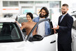 © Prostock-studio - Young indian loving couple choosing car at luxury auto dealership
