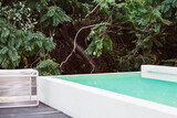 Fototapeta  - A beautiful minimalist infinite swimming pool surrounded by greeneryin Cuernavaca, Morelos. The clear water invites you to swim, and the tall green trees around offer a nice break from the sun.