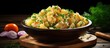 Traditional German potato salad with onion and chives served as close up in a design bowl on a rustic black board. Creative Banner. Copyspace image