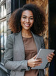 © ChanelBot/Peopleimages - AI - Woman, tablet and business portrait in an office for management, entrepreneur and corporate planning. Confident, female executive standing alone for portrait, strategy and leadership in workplace