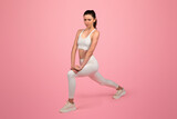 Fototapeta Panele - Focused woman in white athletic wear performing a stretching exercise in a lunge position