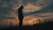 Silhouette of a person standing in a field at sunset. Perfect for nature or inspirational themes
