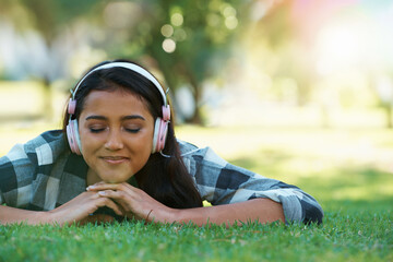 Wall Mural - Music headphones, park or woman on grass to relax for rest in garden, nature or field with smile or peace. Eyes closed, streaming or calm person on break with playlist for radio, podcast or wellness