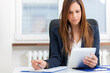 © Minerva Studio - Professional woman working on tablet at office desk