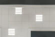 © hiv360 - cassette stretched or suspended ceiling with square halogen spots lamps and drywall construction in empty room in house or office with column. Looking up view