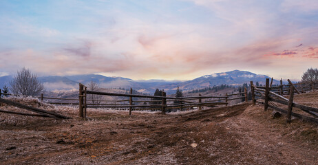 Wall Mural - Winter coming. Last days of autumn, morning in mountain countryside peaceful picturesque hoarfrosted scene. Dirty road from hills to the village. Ukraine, Carpathian mountains.