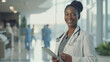 © MP Studio - smiling female healthcare professional, stands in a hospital corridor holding a tablet