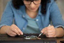 woman making precision repair on laptop using tweezers
