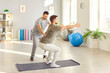© Studio Romantic - Male nurse, caregiver or physiotherapist helping young man in doing sport exercise on yoga mat in rehabilitation clinic supporting him in rehab. Physiotherapy and recovery concept concept.