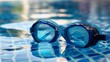 © Artsaba Family - Close-up of blue swimming goggles with water droplets on pool edge, reflecting the sky.