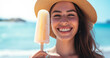 © Vitor - mulher jovem feliz com chapéu de palha e óculos escuros tomando sorvete na praia