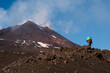 Man with backpack with Sicily Etna volcano behind him