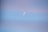 Fototapeta Morze - Młody księżyc wśród chmur wieczorem
