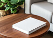 © NK Project - Advertising close up mockup shot of book lying on dark wooden coffee table with white sofa and green plant at the background