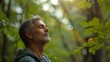 © Marc - Relaxed adult man breathing fresh air in a forest with green trees in the background