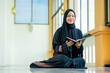 © maya1313 - Ramadan, The image of an Asian Muslim woman in the Islamic religion in hijab in black color. reading the Quran and having a happy smiling face Staying in a beautiful mosque out of respect for God.