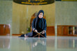 © maya1313 - Ramadan, The image of an Asian Muslim woman in the Islamic religion in hijab in black color. reading the Quran and having a happy smiling face Staying in a beautiful mosque out of respect for God.
