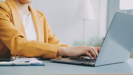 Wall Mural - Woman hand holding white mobile phone on a table with a laptop in office.