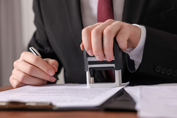 Poster - Notary with pen stamping document at table in office, closeup