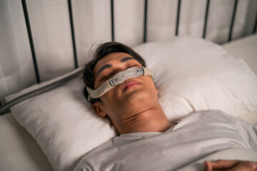 Wall Mural - Asian man wearing cpap machine sleeping smoothly all night in bedroom. 