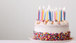 © wanchai - White birthday cake with vibrant polka dot candles and scattered confetti on a clean background.