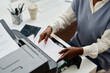 © TrueFrame Collective - High angle view of unrecognizable young Black woman working in office putting paper onto printer tray