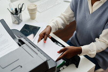 High Angle View Of Unrecognizable Young Black Woman Working In Office Putting Paper Onto Printer Tray