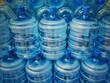 Stack of empty water bottles jugs in a warehouse, close up details. Purified water battles for return.