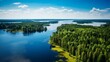 Aerial view of road with green woods by blue lakes water in summer Finland