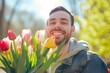 smiling man with a mix of tulips outdoors on sunny day